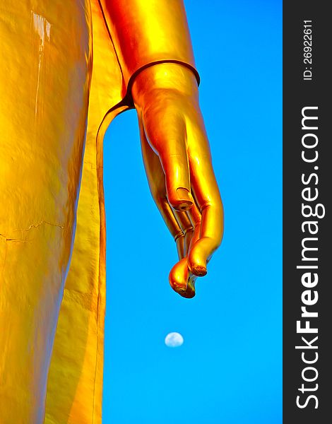 A large golden statue of Buddha with his hand reaching out to the moon. A large golden statue of Buddha with his hand reaching out to the moon.