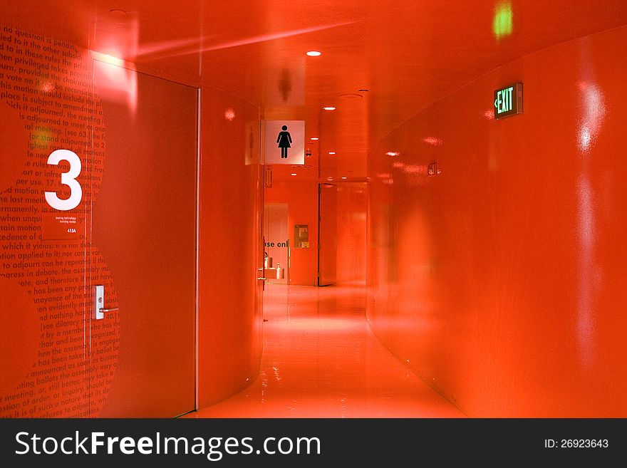 A totally red hallway with bathroom and exit sign