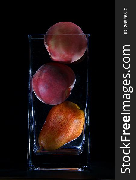 Pears and peaches in a vase on a black background. Pears and peaches in a vase on a black background.
