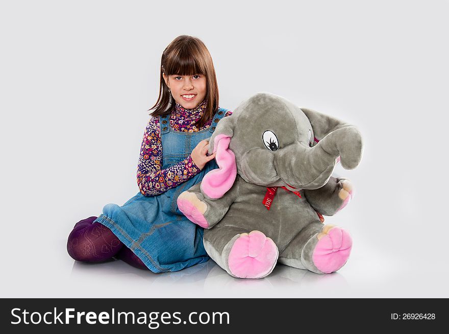 Cheerful girl playing with an elephant toy on white background