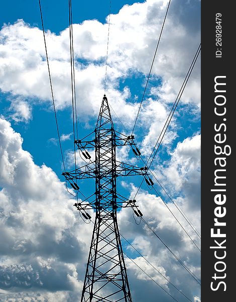 Mast of a high-voltage power line against the dark blue sky with clouds. Mast of a high-voltage power line against the dark blue sky with clouds