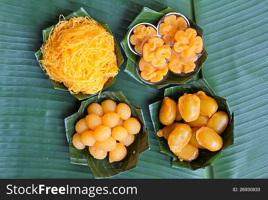 Thai assorted desserts which thier names are inspired by gold series. Foitong (Golden Hair), Tongyip (Tiny Gold Flower), Tongyod (Drops of Gold), Medkanoon (Gold Jackfruit seed). Presented on green banana leaf cups.