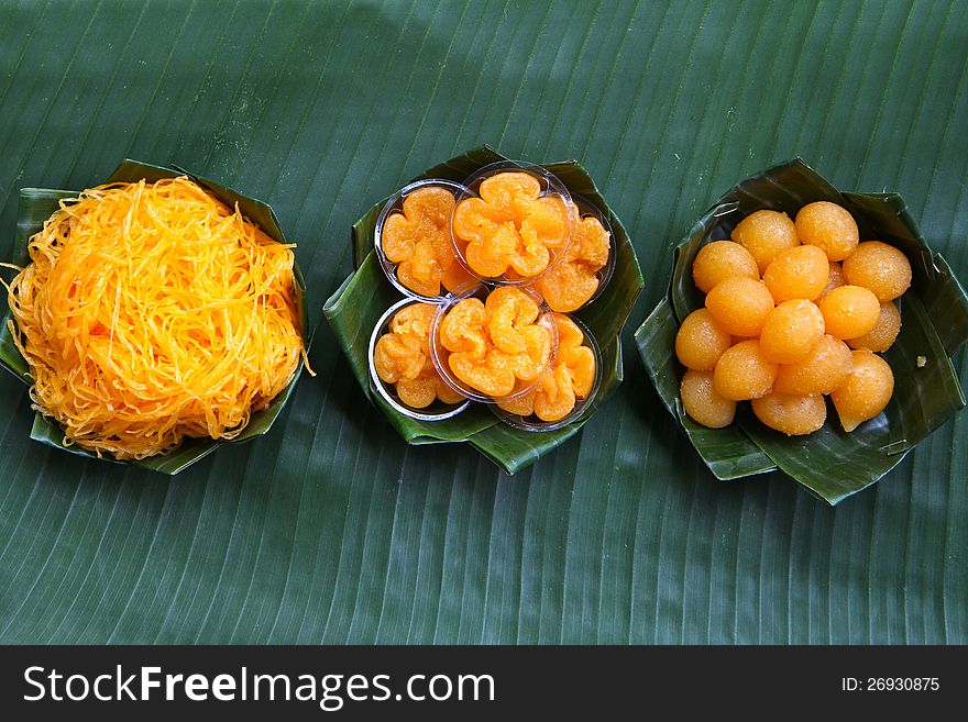 Thai assorted desserts which thier names are inspired by gold series. Foitong (Golden Hair), Tongyip (Tiny Gold Flower), Tongyod (Drops of Gold). Presented on green banana leaf cups.