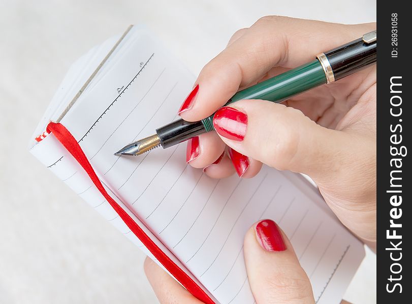 Close Up Of A Female Hand Holding A Pen About To Take Notes On A Blank Note Pad. Close Up Of A Female Hand Holding A Pen About To Take Notes On A Blank Note Pad