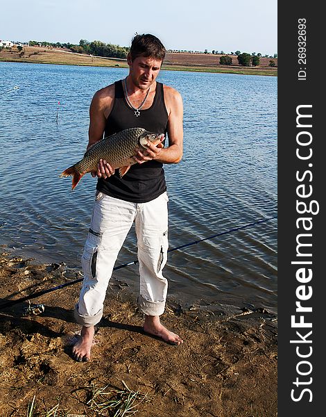 Fisherman with his big carp at a beautiful river.