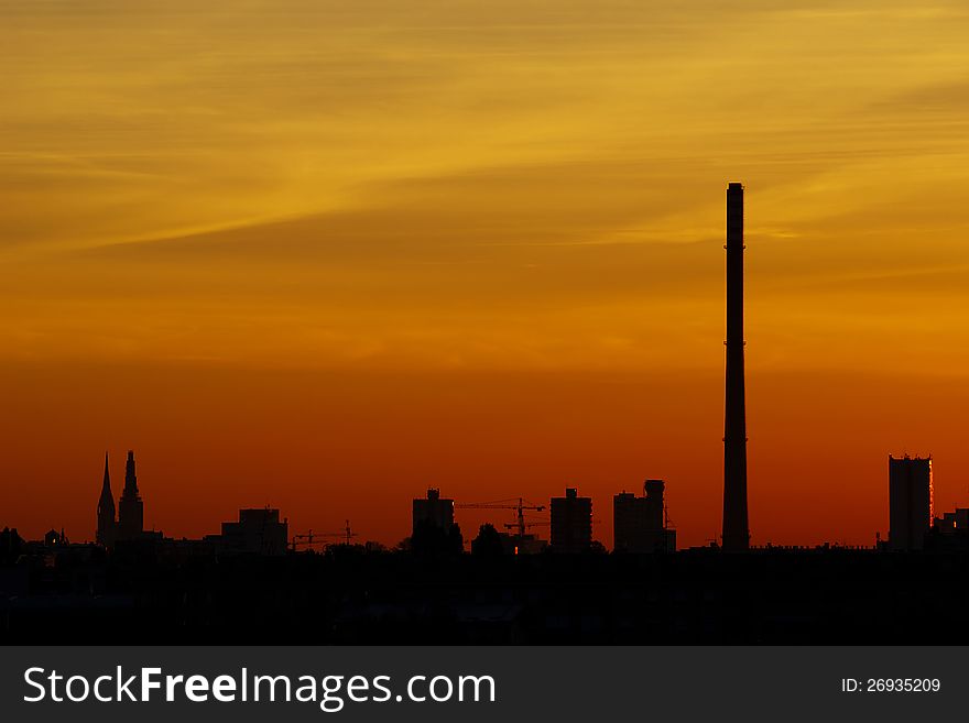 Orange sky above city of Zagreb in Croatia before sunrise with silhouettes of Cathedral, apartment blocks and thermal power plant chimney. Orange sky above city of Zagreb in Croatia before sunrise with silhouettes of Cathedral, apartment blocks and thermal power plant chimney.