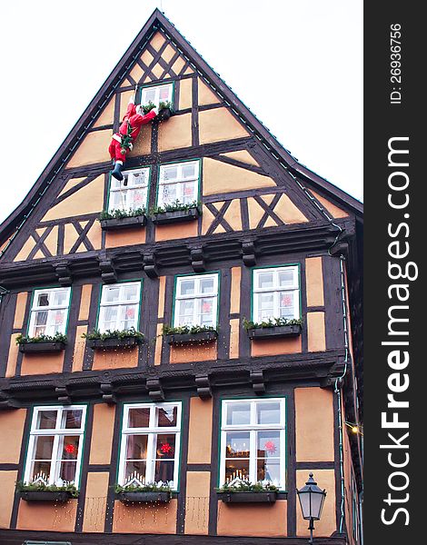 Santa Claus climbing up house wall at european town