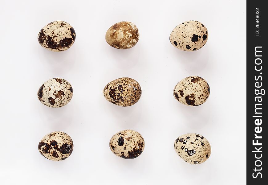 Nine quail eggs on a white background