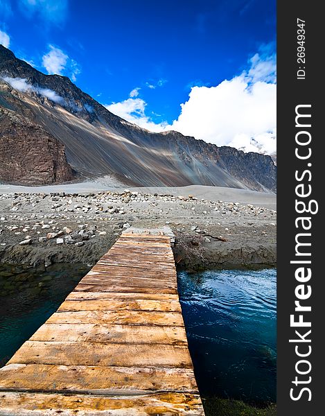 Mountain landscape view with river and wooden bridge over evening blue sky. India, Ladakh, Nubra Valley