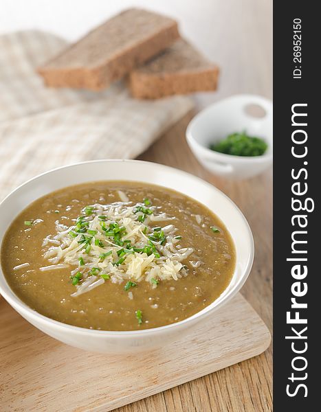 Lentil soup with cheese and green onions on a wooden table