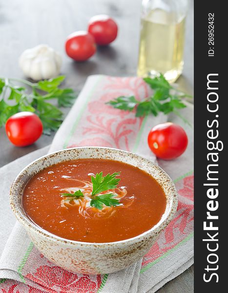 Hot tomato soup in ceramic bowl on the table, covered with a napkin