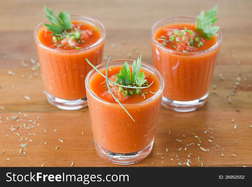 Cold tomato soup, portionwise, in glass jars decorated with greenery