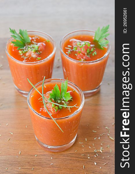 Cold tomato soup, portionwise, in glass jars decorated with greenery