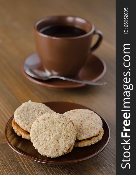 Walnut cookies on brown ceramic plate with a cup of coffee