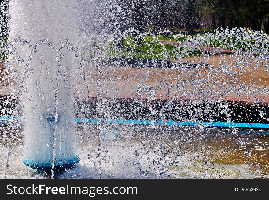 Sparkling splashes of a fountain in the bright sunny summer day. Sparkling splashes of a fountain in the bright sunny summer day