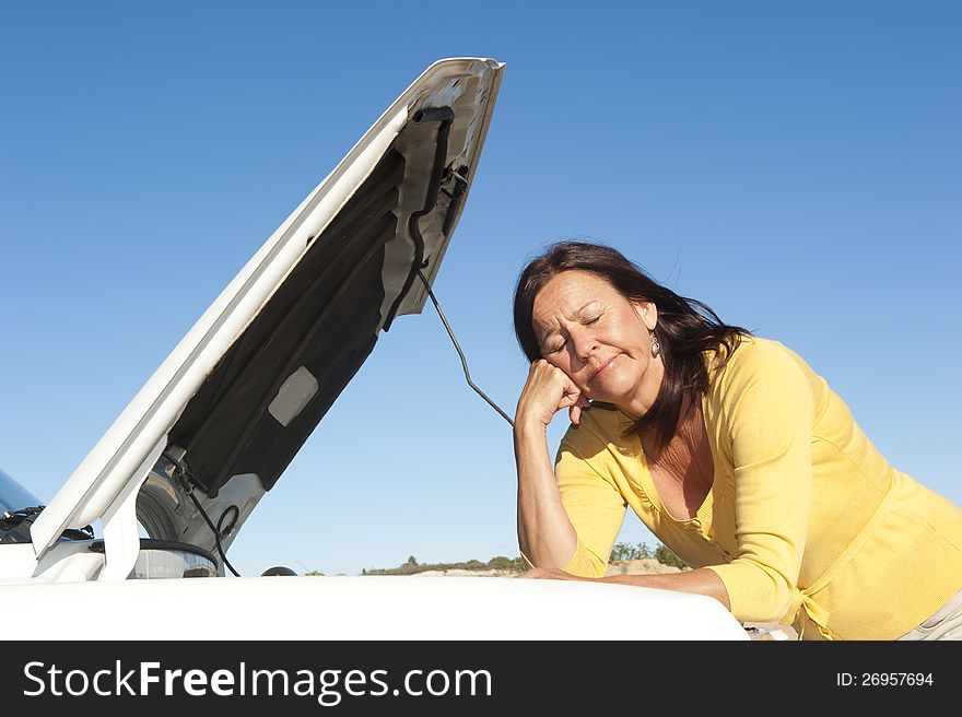 Stressed mature woman breakdown with car on remote road waiting for assistance, for help, isolated with blue sky as background and copy space. Stressed mature woman breakdown with car on remote road waiting for assistance, for help, isolated with blue sky as background and copy space.