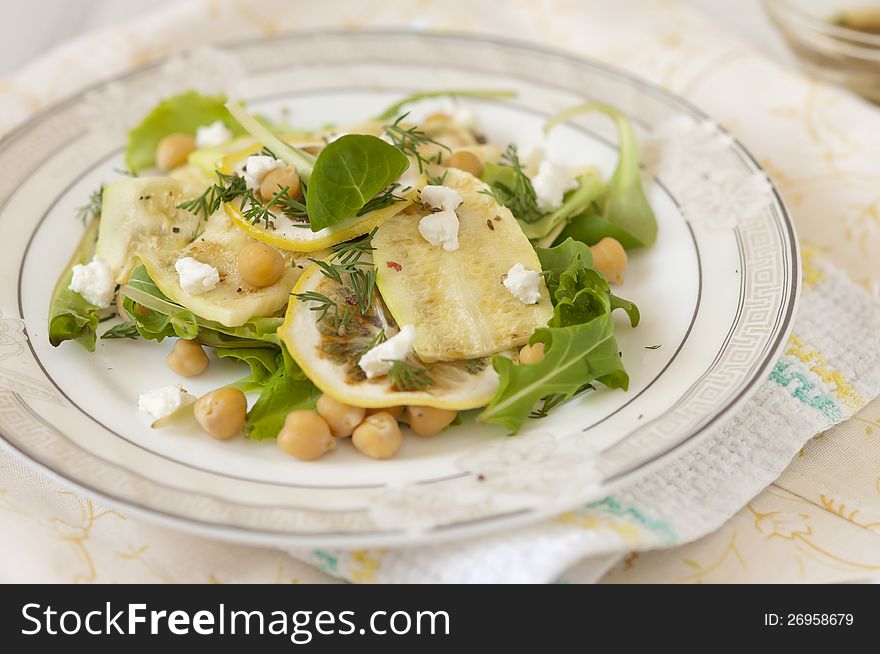 Chickpea salad with grilled zucchini and arugula on a white plate on a napkin. Chickpea salad with grilled zucchini and arugula on a white plate on a napkin