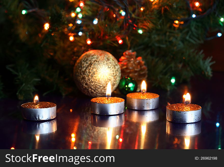 Few lighting candles on background with fir tree and colored lamps. Few lighting candles on background with fir tree and colored lamps