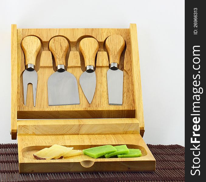 Slices of cheese on a cutting plank and knives for cutting