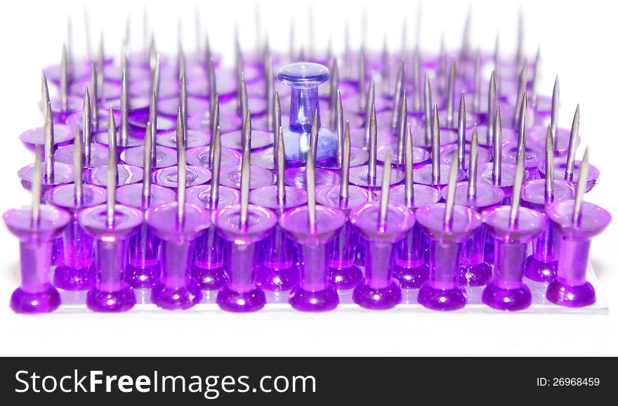 Purple push pins close-up on white background standing points up with one different in the middle