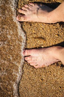 Men S Feet Are Standing On A Sandy Beach. Small Waves Are Foaming On The Seashore. Crystal Clear Water. Royalty Free Stock Photo Men S Feet Are Standing On A Sandy Beach. Small Waves Are Foaming On The Seashore. Crystal Clear Water. Royalty Free Stock Photo