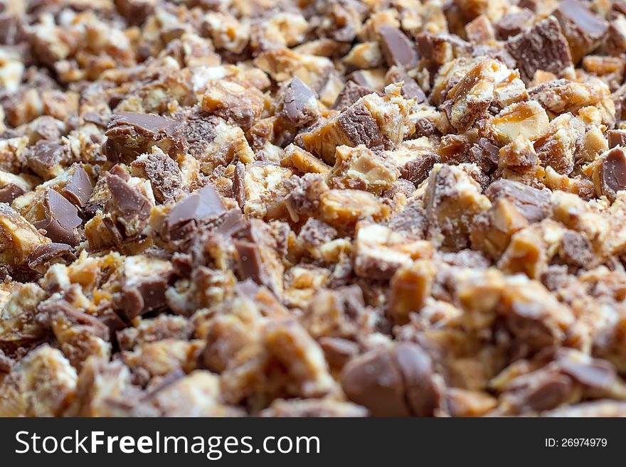 Closeup image of chopped bars of chocolate, caramel and biscuit