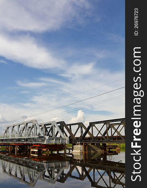 Both the new and old steel railway bridge reflection water clouds sky background. Both the new and old steel railway bridge reflection water clouds sky background.