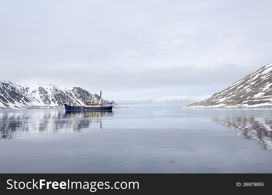 A tourist boat anchored in a beautiful bay, surrounded by Spitsbergen, Svalbard. A tourist boat anchored in a beautiful bay, surrounded by Spitsbergen, Svalbard.