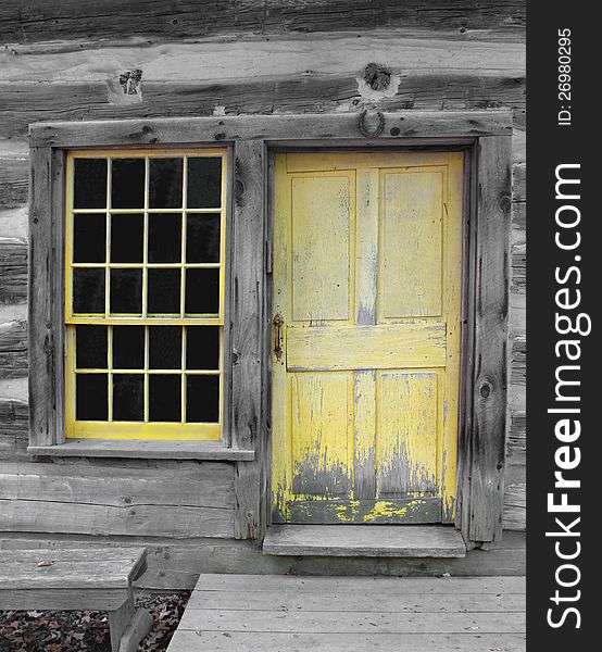 Close-up of an old weathered yellow wooden door and window in a gray wood log building. Close-up of an old weathered yellow wooden door and window in a gray wood log building.