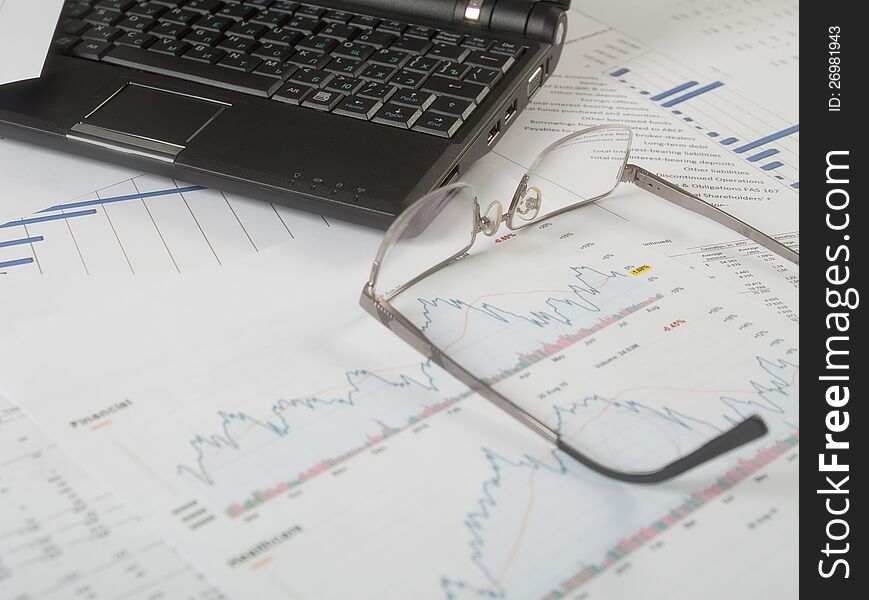 Laptop and glasses on business papers