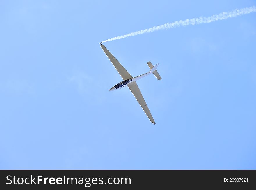 Sports glider aerobatic pilot flying in the sky with blue racing with trail of white smoke. Sports glider aerobatic pilot flying in the sky with blue racing with trail of white smoke