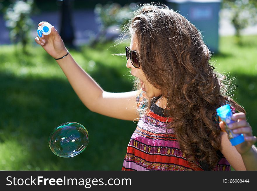 Young girl blows soap bubbles