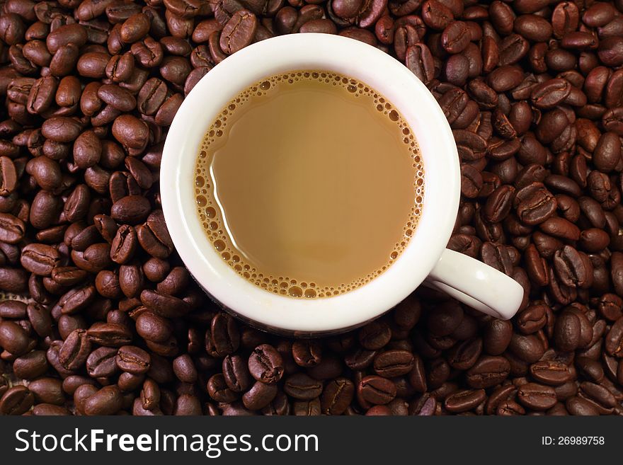 A cup of coffee milk with coffee bean as background. A cup of coffee milk with coffee bean as background