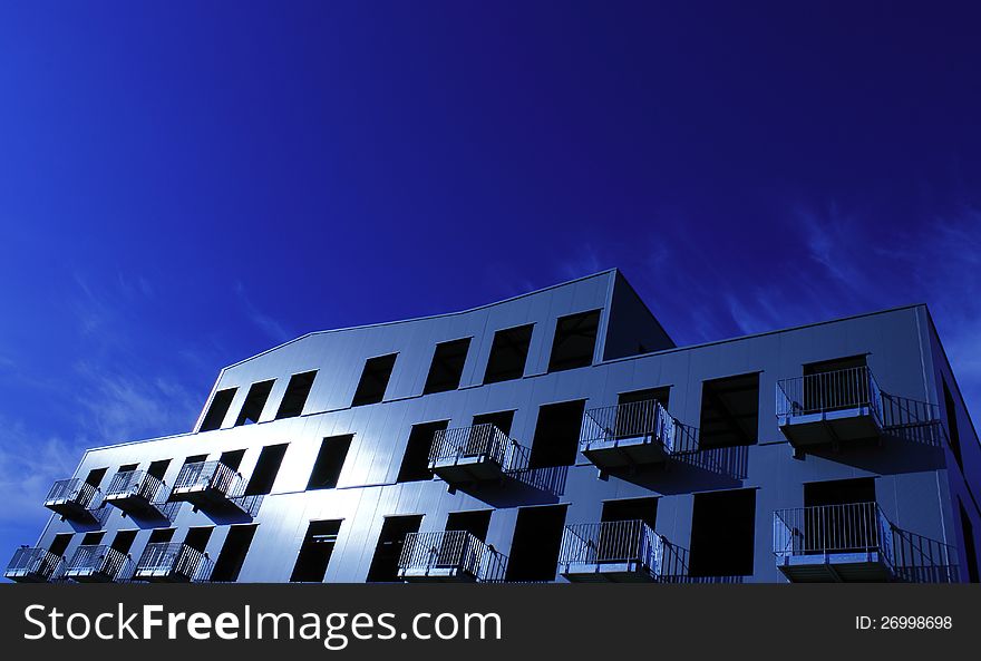 Building with balconies on a blue background in the midday sun. Building with balconies on a blue background in the midday sun