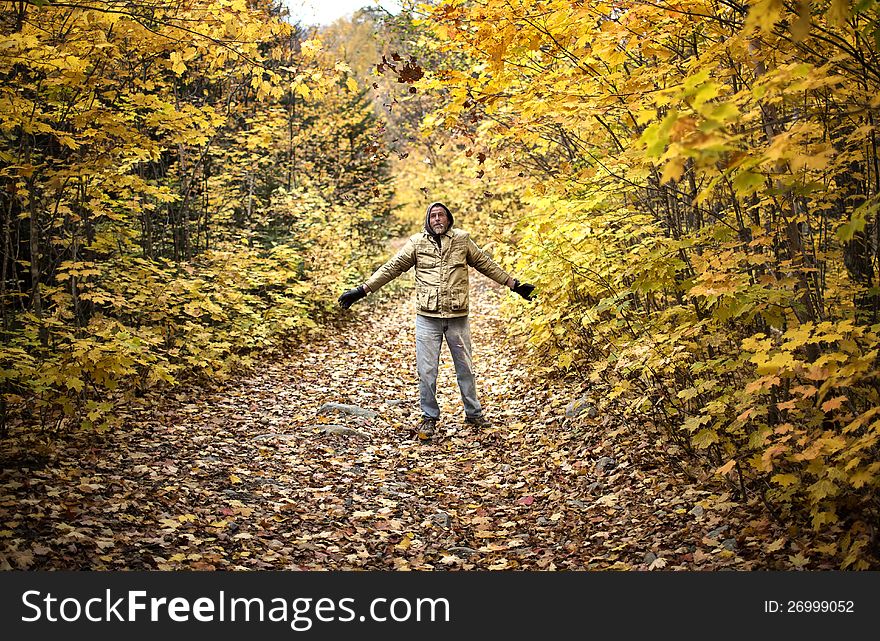 A man throwing leaves in the air on a walk through the woods in Autumn. A man throwing leaves in the air on a walk through the woods in Autumn.