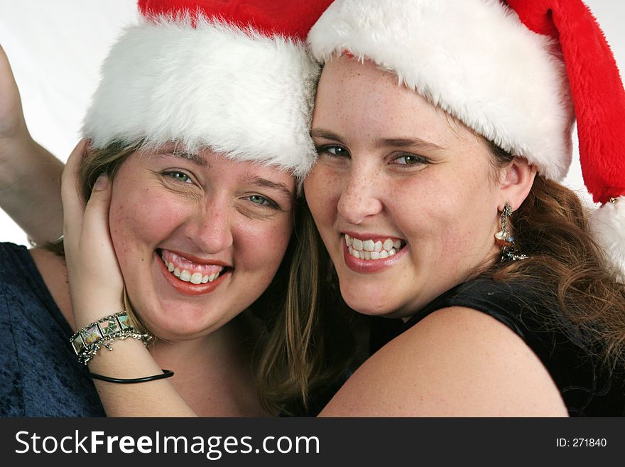 Two pretty girls in Santa hats laughing. Two pretty girls in Santa hats laughing.