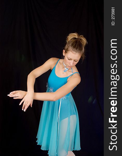 Ballerina in 3/4 pose with black background with blue costume. Ballerina in 3/4 pose with black background with blue costume