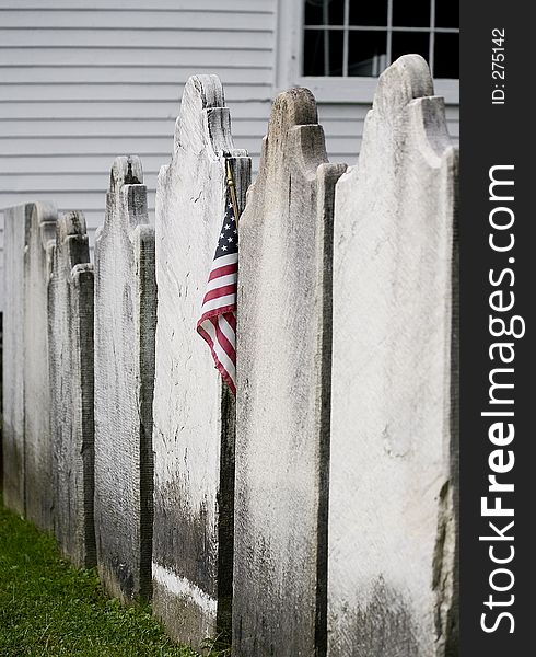 A lonely American flag is placed in the midst of unmarked tombstones. A lonely American flag is placed in the midst of unmarked tombstones