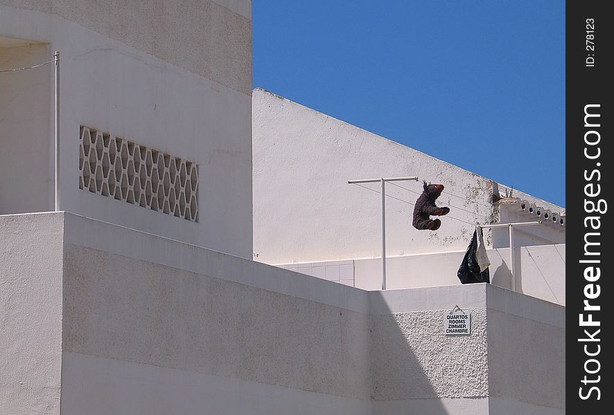 A teddybear hanging on a clothes line on a sunny roof terrace. A teddybear hanging on a clothes line on a sunny roof terrace.