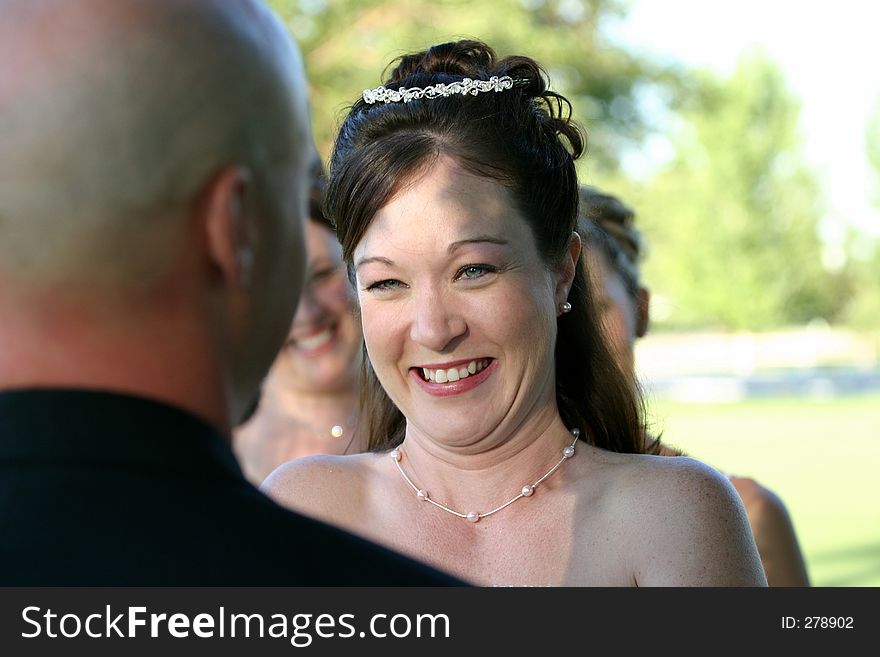 A wedding ceremony in full swing, this is a happy bride taking her vows. With focus on her bright smile and laughter, her husband to be and bridesmaids fill out the scene. A wedding ceremony in full swing, this is a happy bride taking her vows. With focus on her bright smile and laughter, her husband to be and bridesmaids fill out the scene.