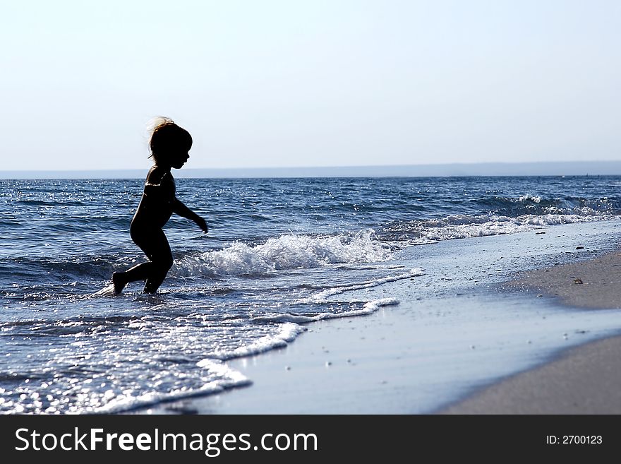 Silhouette of running baby in the sea