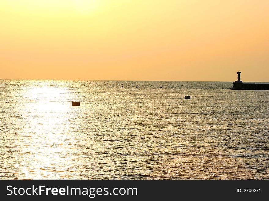 Golden sunset on sea with lighthouse