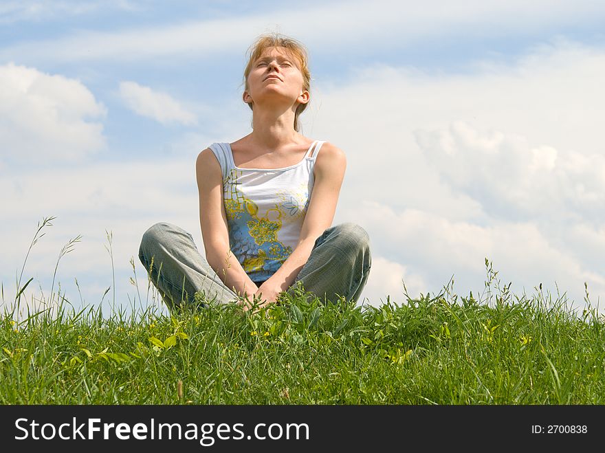 The red girl has a rest at top of a hill, sitting in a grass. The red girl has a rest at top of a hill, sitting in a grass