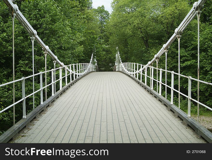 Old, white suspension bridge in a forest, made of wood and iron. Old, white suspension bridge in a forest, made of wood and iron.