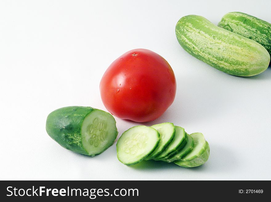 Fresh sliced cucumbers and tomato over white. Fresh sliced cucumbers and tomato over white