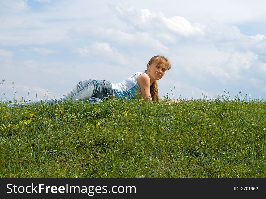 The red girl has a rest at top of a hill, lays in a grass. The red girl has a rest at top of a hill, lays in a grass