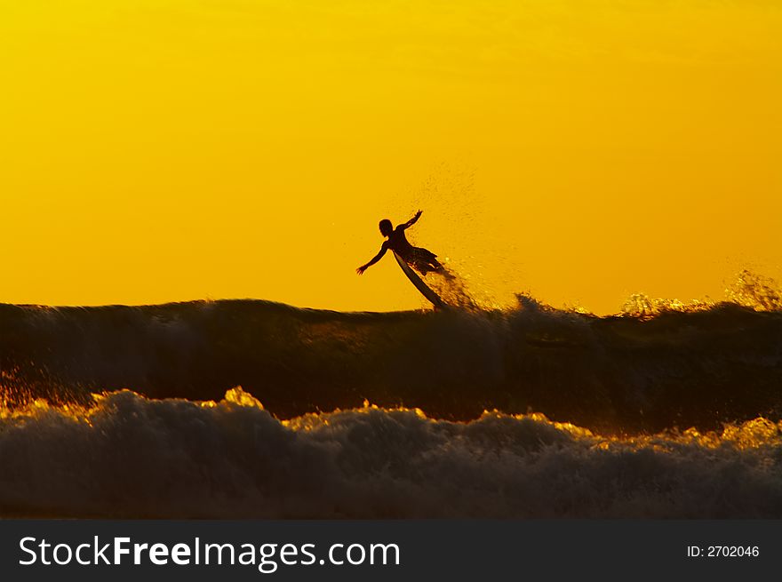 Silhouette of the surfer flying above the wave during sunset. Silhouette of the surfer flying above the wave during sunset