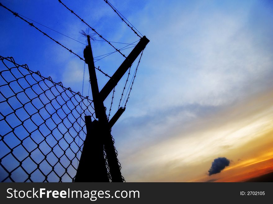 A fence used as a security in silhouette during sunset . A fence used as a security in silhouette during sunset .