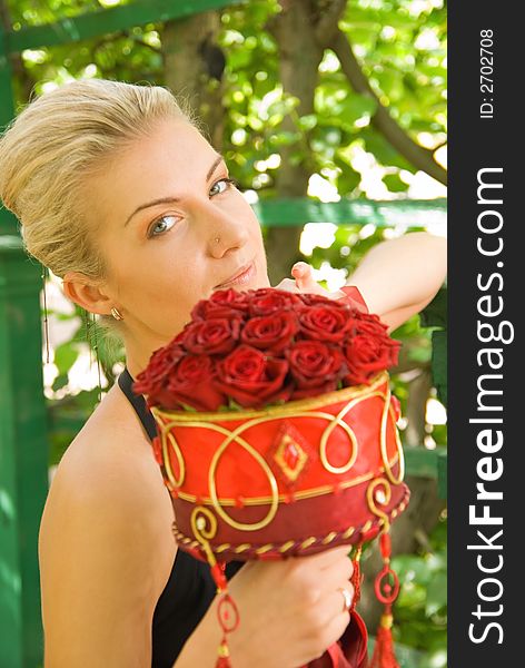 Beautiful blond girl with a bouquet of red roses
