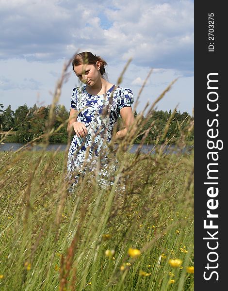 Young beautiful girl sitting on the grass in the field in summer warm day. Young beautiful girl sitting on the grass in the field in summer warm day